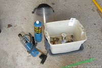 Wide view showing the welding face mask, two propane canisters, plastic storage bin with tools and flux