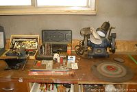 Bench with Mastercraft 6-inch bench grinder, assortment of drill bits, grinder wheels, and other tools arranged on top