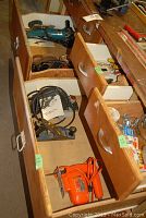 Photo of open drawers containing various power tools including Black and Decker jigsaw, Skil planer, Makita disc grinder and adjustable hand plane