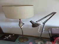Side view of both lamps: Mid-Century Modern lamp with beige shade and ceramic base, metal adjustable reading lamp beside it.