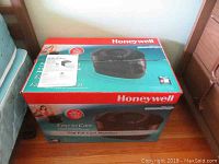 Boxed Honeywell Easy to Care humidifier with user manual on top, shown near bed frame.
