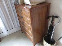 Side view of tall wooden high boy dresser showing four drawers and carved drawer fronts.
