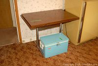Full view of Arborite table with metal base beside kitchen cabinetry showing table size and leaves.