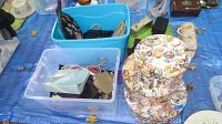 Blue storage bins containing various vintage handbags and cylindrical floral printed hat boxes on a blue tarp.