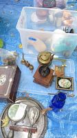 Photo showing assorted vintage and antique items including brass bells, coffee grinder with teapot, wooden box, and antique keys around a plastic tote