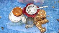 Photo showing multiple copper molds with shiny copper finish, clear and metal containers, and other kitchen items on blue tarp.