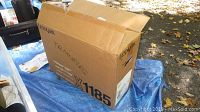 Photo showing Lexmark cardboard box labeled with model and branding, exterior condition and packaging shown.