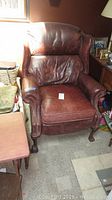 Photo showing entire recliner chair from front and side, highlighting shape, leather wear, and overall condition.