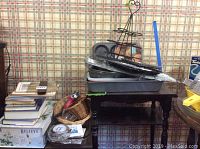 Stacked kitchen books, metal baking racks and pans, cupcake holder tree on a dark wood table.