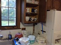 Kitchen sink area showing fondue pot, coffee maker, drinking glasses and Pyrex dishes