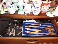 Drawer with various silver flatware pieces including Towle steak knives in original blue box.