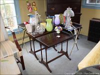 Two vintage wooden side tables with spindle legs and dark wood finish, one closer view showing surface condition. Vintage TV trays with eagle designs partially visible behind, metal legs visible.