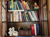 Bookshelves with antique and hardcover books, including the leather-bound 1904 Medicology book, wooden gavel, bust figurines, and ceramic fruit bookends.