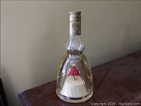 Full view of glass bottle with the dancing ballerina figurine inside on wooden surface.