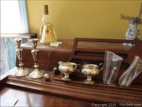 Wide view of all the silver items on display including candlesticks, salt and pepper shakers, sugar and creamer, and rattle