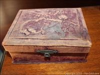 Exterior top view of fabric box showing embossed floral and cherub design on purple faded fabric.