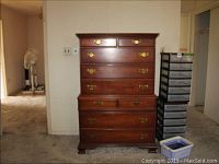 Full front view of the chest on chest dresser showing six drawers with brass handles and crown molding on top.
