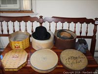 Wide view showing multiple hat boxes, hats, and the vintage beaded purse on wooden bench