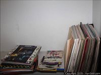 Stack of assorted vinyl LP records and 45 singles laid on a white surface
