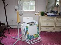 Honeywell floor fan and two foldable sand chairs, plastic bath seat visible behind chairs
