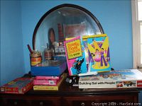 Photo showing multiple boxed items including Barbie Ken, Donnie and Marie TV Show stage, Charlotte's Web game, LEGO Building Set with people, and car case.