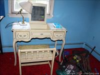 Front and partial side view of the French provincial vanity with matching bench beneath and the marble base brass lamp on top.