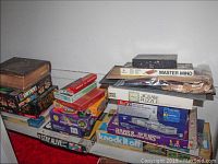 Photo showing stacked board games including Simon, Trump, Stay Alive, Knock It Off, Sorry, Family Feud, Master Mind, and several puzzles including a 3D US Capitol puzzle, alongside a boxed Holy Bible with ornate cover.