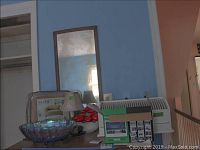 Photo showing slip cover package, carnival glass bowl, ceramic bowl of apples, hula girl figure, and decoy lamp on tabletop