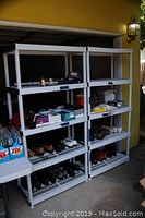 Photo showing two white plastic shelving units standing side by side, each containing various small items on the shelves.