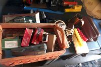 View of assorted staplers, boxes of staples, and some other office desk supplies in wooden box.