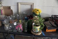 Overview of vases and plants on table with empty picture frame behind