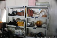 Two gray plastic shelving units next to each other containing various household items such as cloth, baskets, and containers.