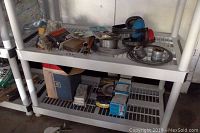 Shelf with assorted automotive parts including carburetor and spools of wire