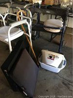 Photo shows largest chair, white shower chair, two walkers, mobility scooter seat, and cane.