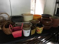 Multiple outdoor pots and baskets displayed together, showing variety of sizes and materials