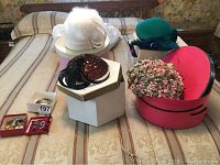 Vintage hats and jewelry displayed on a bed, showing different hats and costume jewelry pieces.