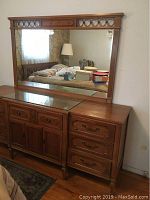 Front view of wooden dresser with large attached mirror reflecting part of room