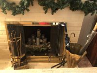 Fireplace screen, fireplace tools, and umbrella stand in front of fireplace, showing overall setup.