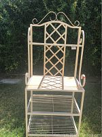Front view of white metal decorative rack in outdoor setting