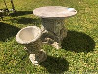 Front view of marble top end table on grassy surface alongside matching planter