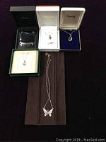 Five sterling silver necklaces displayed in boxes and on a brown cloth.