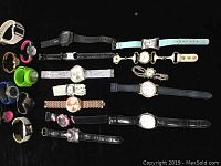 Full lot arranged on black background showing various quartz wristwatches in different styles and band materials including leather, metal, plastic, and fabric.