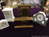 Lot of 5 assorted clocks including brass Swiza, Limoges, Bulova and others on table