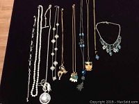 Lot of 10 necklaces displayed on black background, shows pearl strands, animal pendants, and beaded designs