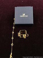 Photo of Swarovski branded box with bracelet and brooch placed beside it on a surface.