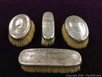 Top view of all four antique sterling silver brushes showing monogram and floral engraving with bristles