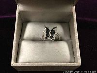 Close-up of the butterfly ring inside a white ring box showing diamond and black gemstone details on the wings.