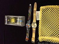Lot of three Swatch watches, two outside packaging showing straps and dials, one in original packaging, netted yellow pouch included.