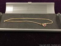 Full view of the 10-inch 14K gold ankle bracelet laid flat on foam inside a silver tray.