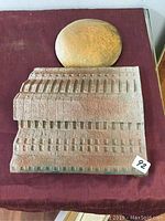 Front view of painted clay architectural artwork with rounded top section, showing detailed textured architectural elements in earthy tones.